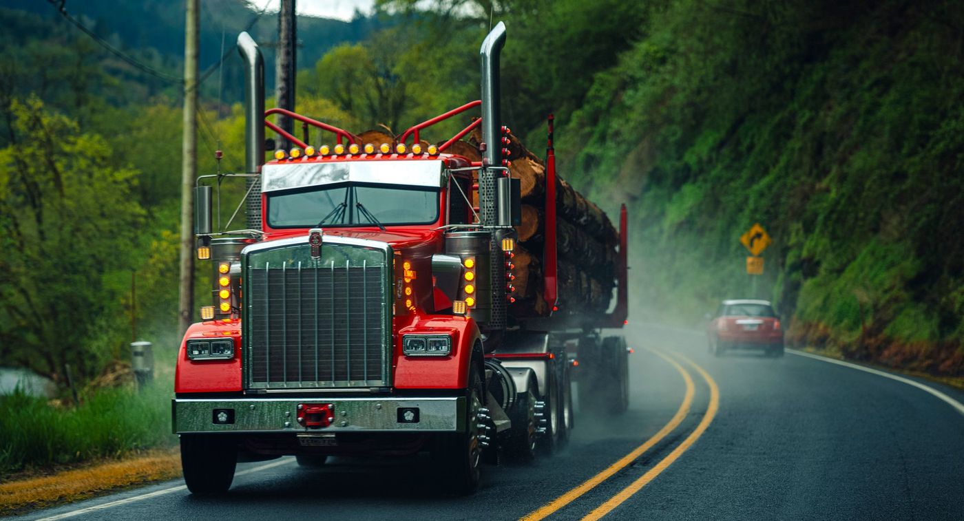 A loaded truck working around a wet curve on a mountain highway.
